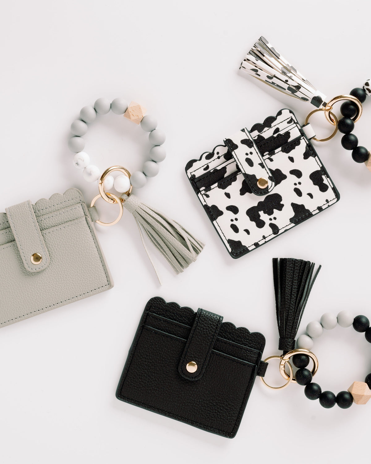 Gray, cow-print, and black wallet wristlet keychains with tassels and beaded keyrings