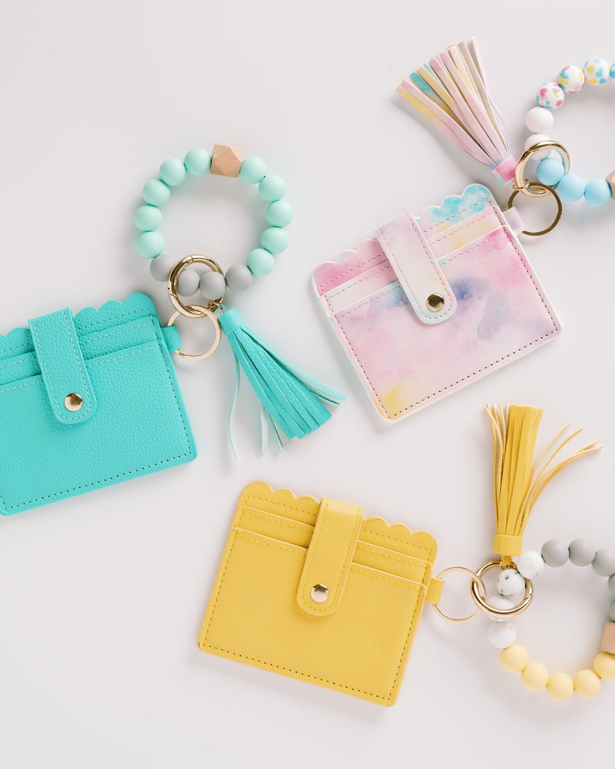 Turquoise, pastel pink, and yellow wallet wristlet keychains with tassels and beaded rings