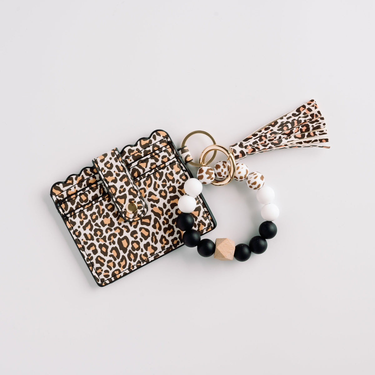 Leopard print wallet wristlet keychain with tassel and black-and-white beaded bracelet.