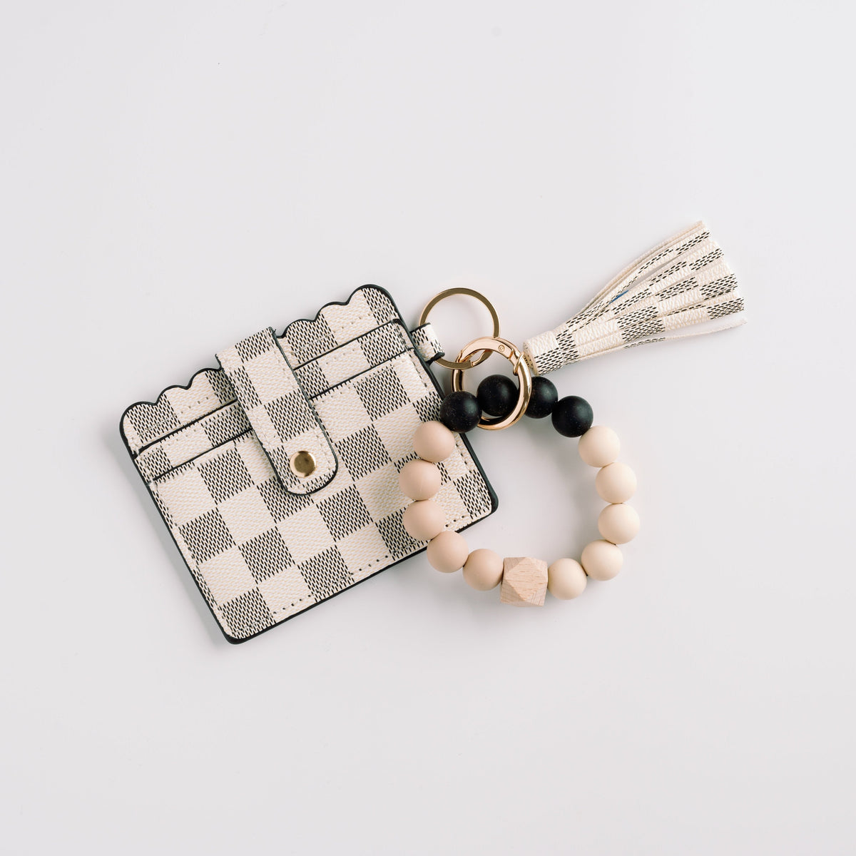 Cream check wallet wristlet keychain with tassel and black-and-white beaded charm.