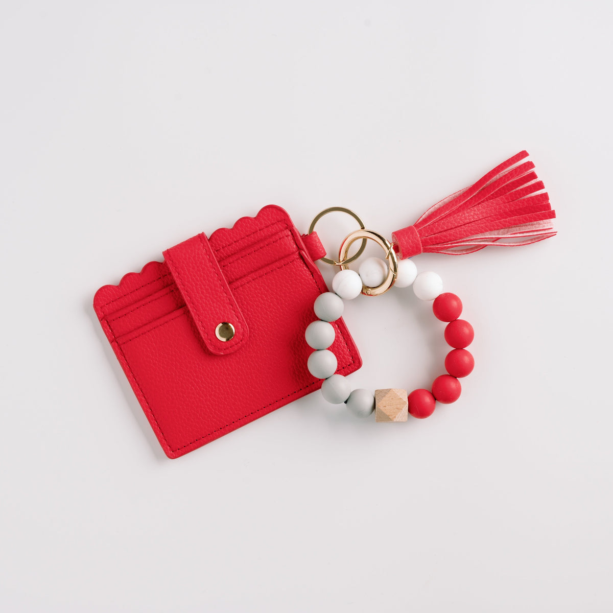 Red wallet wristlet keychain with red tassel and beaded white-and-red bracelet.