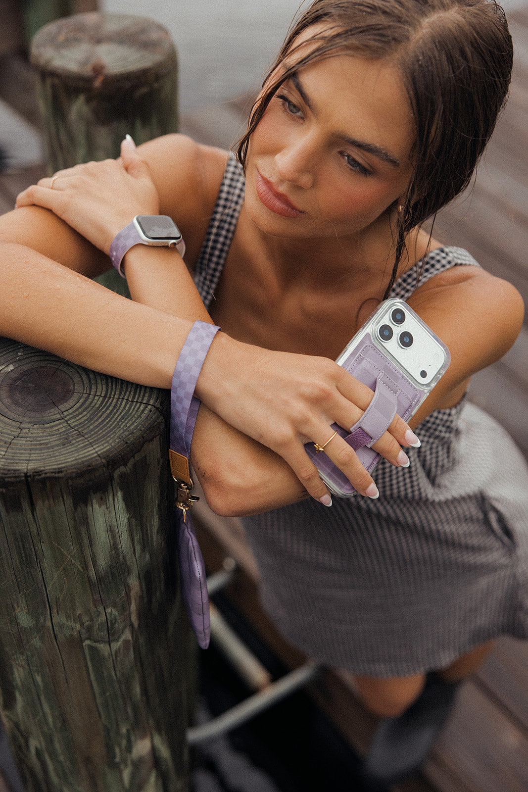 Purple checkered zipper pouch with strap held near a smartphone