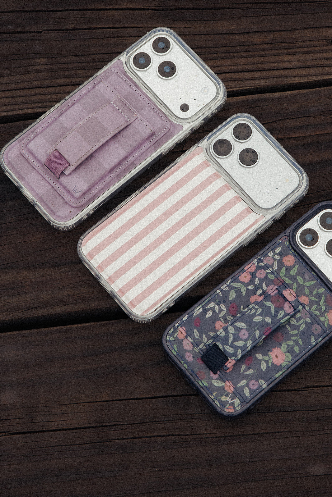 Magnetic phone wallets in lavender and pink with card slots, displayed on dark wood.