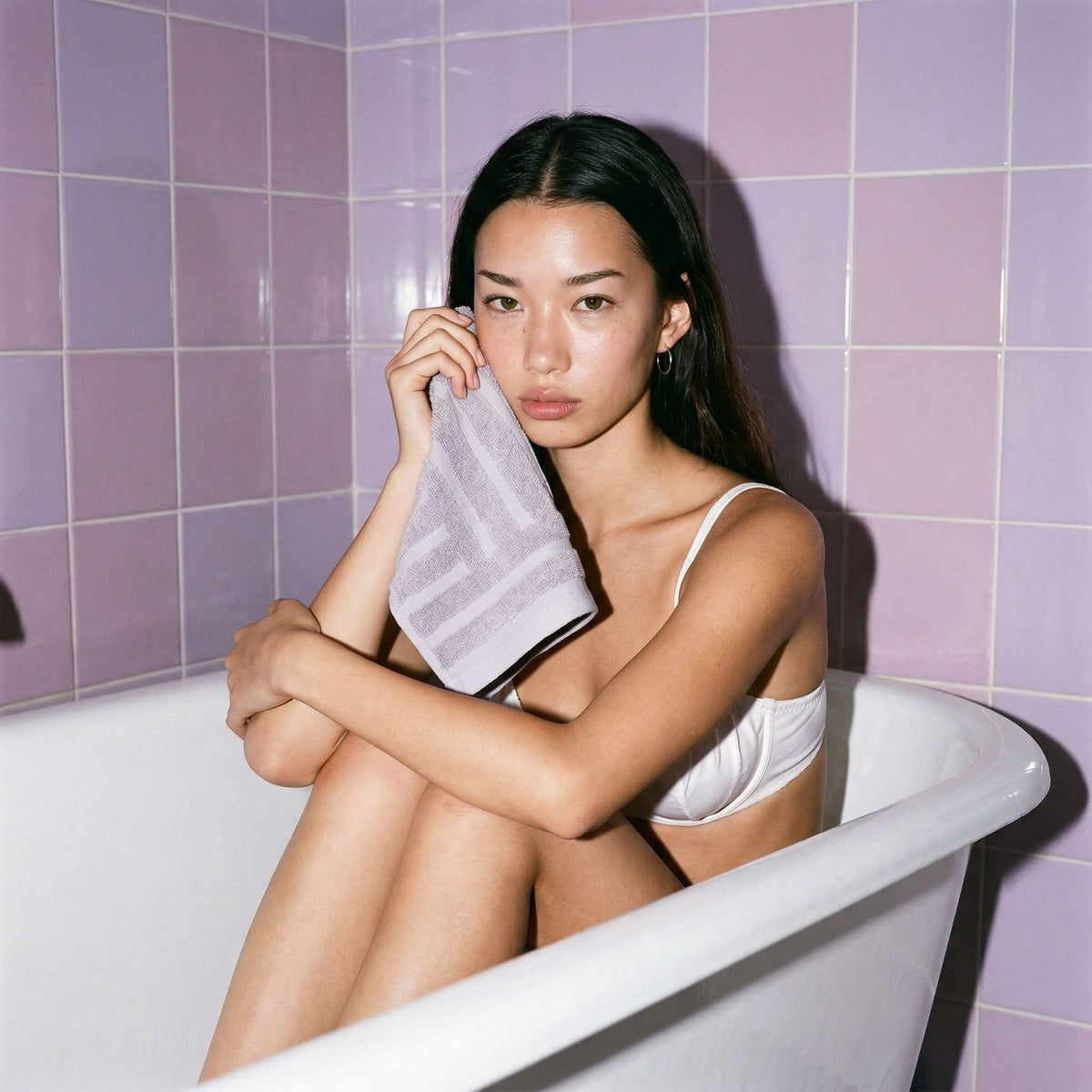 Light gray cotton hand towel, terry texture, held near cheek