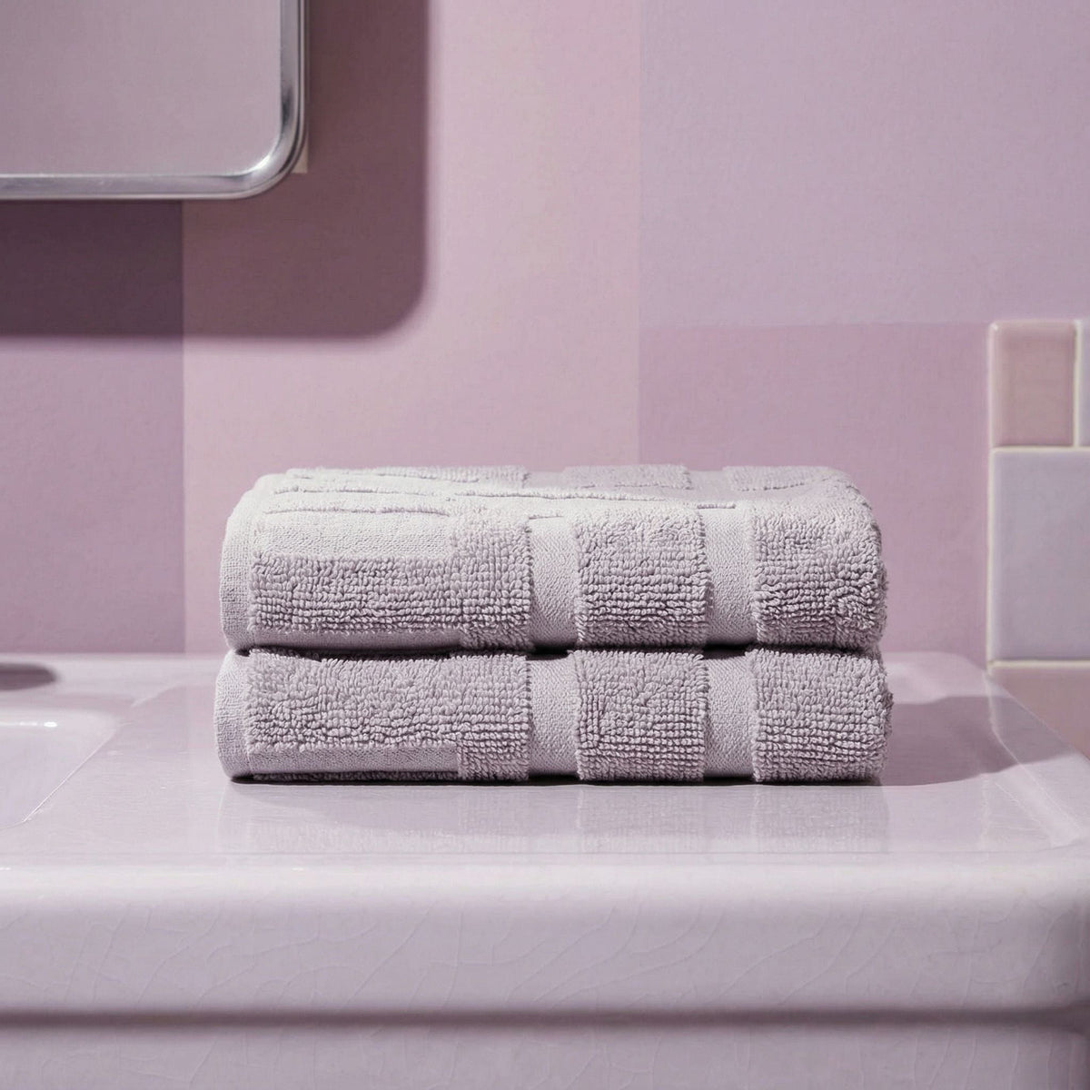 Light gray cotton towels, folded with stitched stripe bands on a glass surface