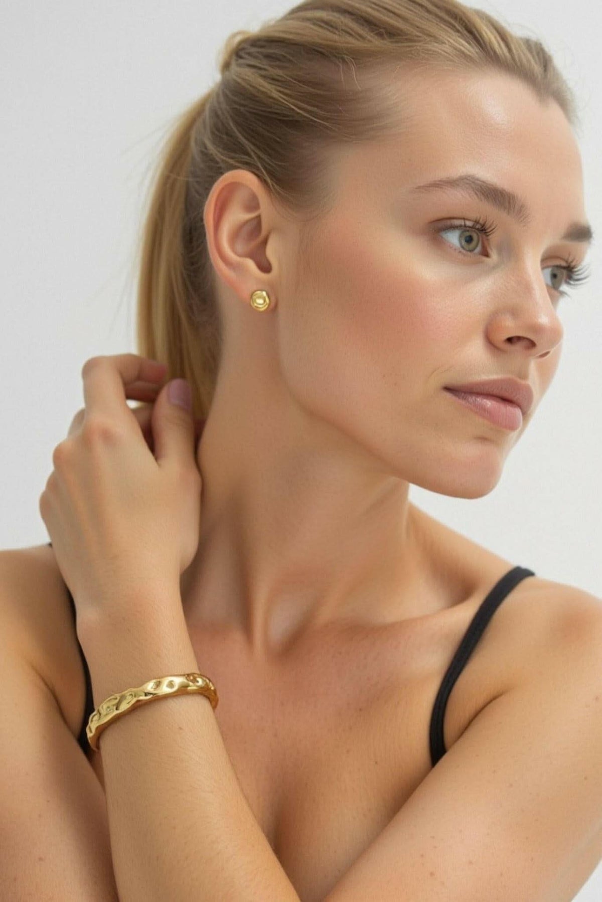 Gold textured cuff bracelet worn on wrist, open wavy edge design