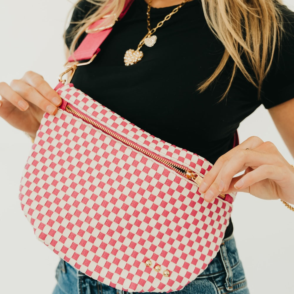 Pink and white woven checkered bum bag with zipper closure and crossbody strap.