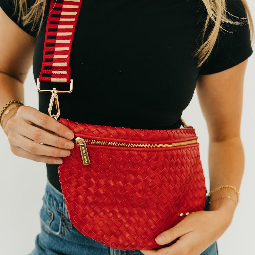 Red woven bum bag with zipper closure and adjustable crossbody strap.