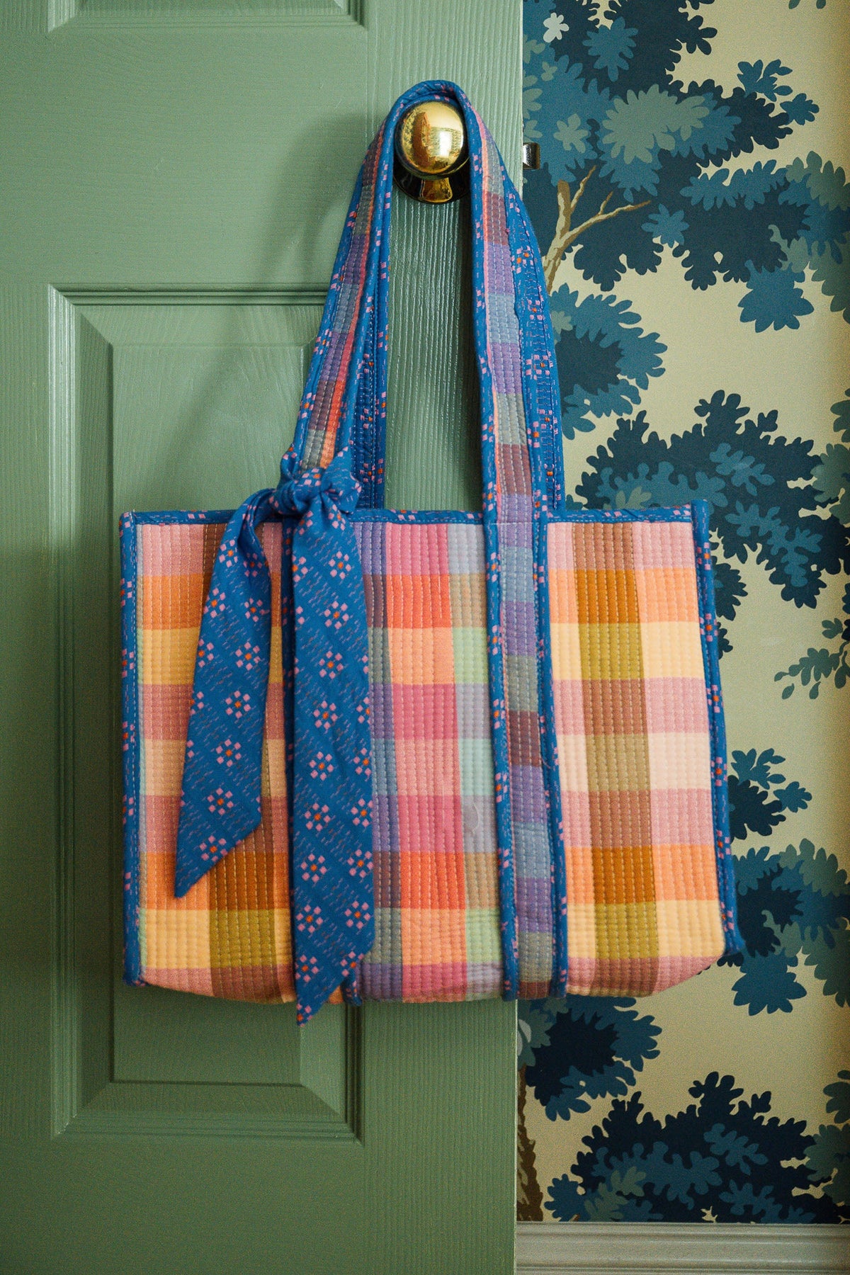 Plaid woven tote bag with blue tie closure and long braided handles