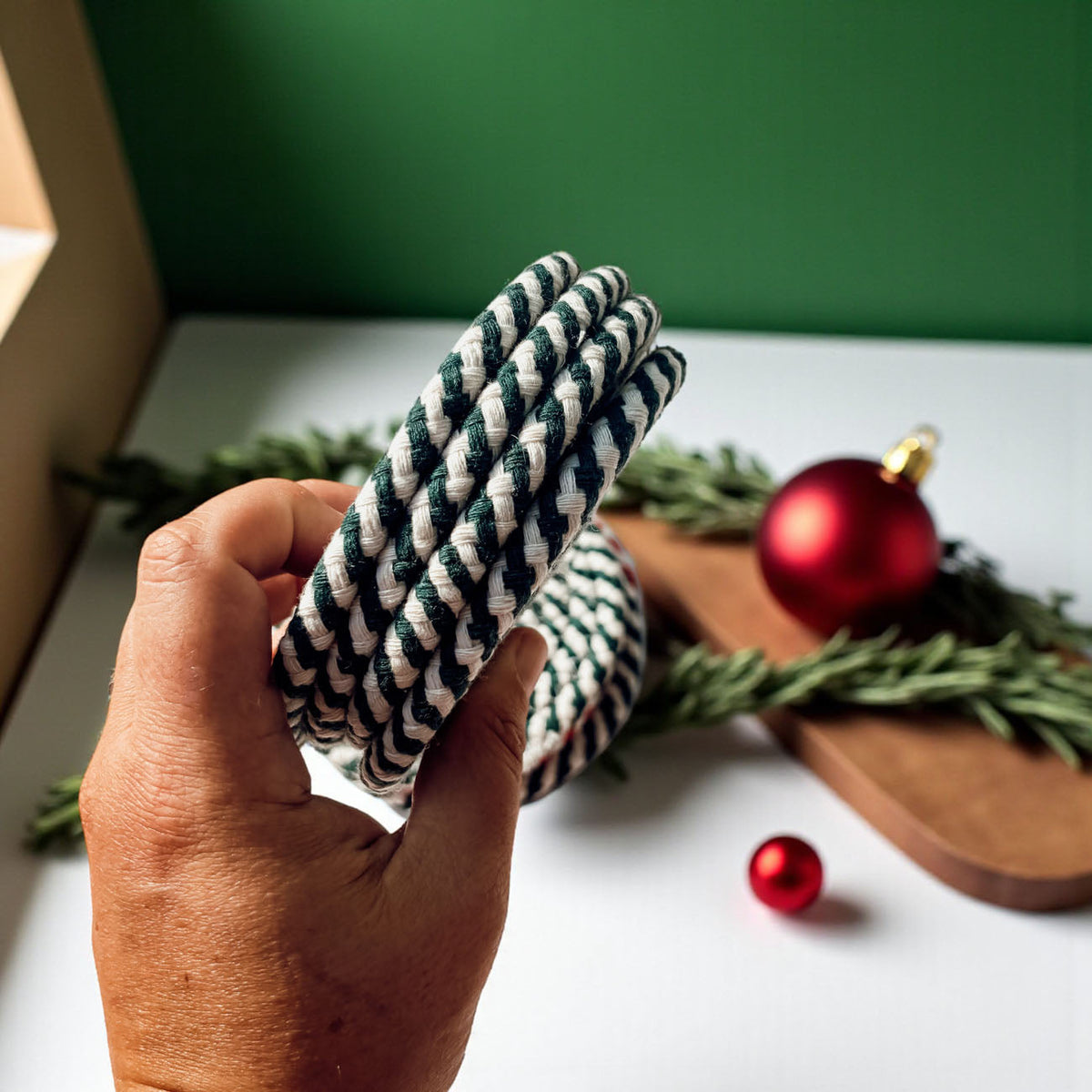 Woven braided fabric coaster, striped teal and white, held in hand