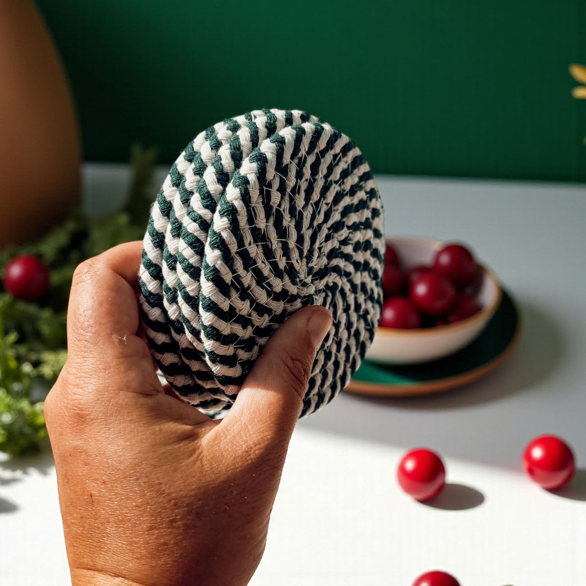 Hand holding a round woven coaster with navy-and-white striped pattern