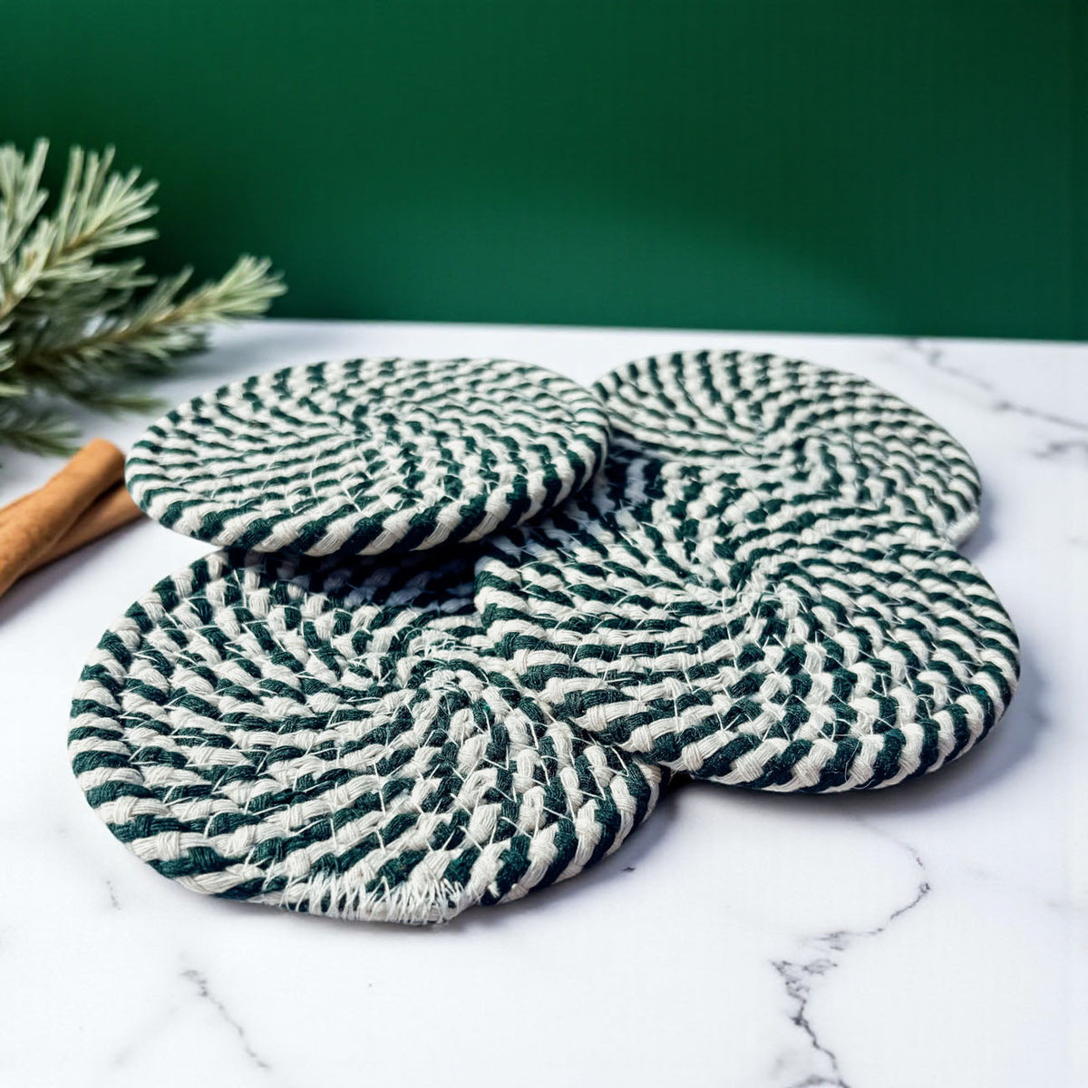 Stacked striped braided coasters, teal and white, close-up on marble