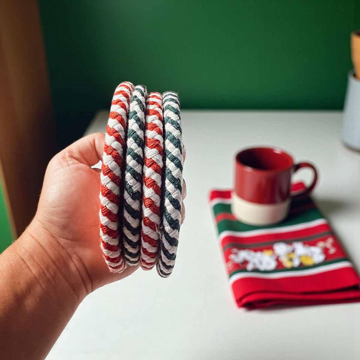 Coaster set (4-pack) with round red-and-white striped coasters, stacked in hand
