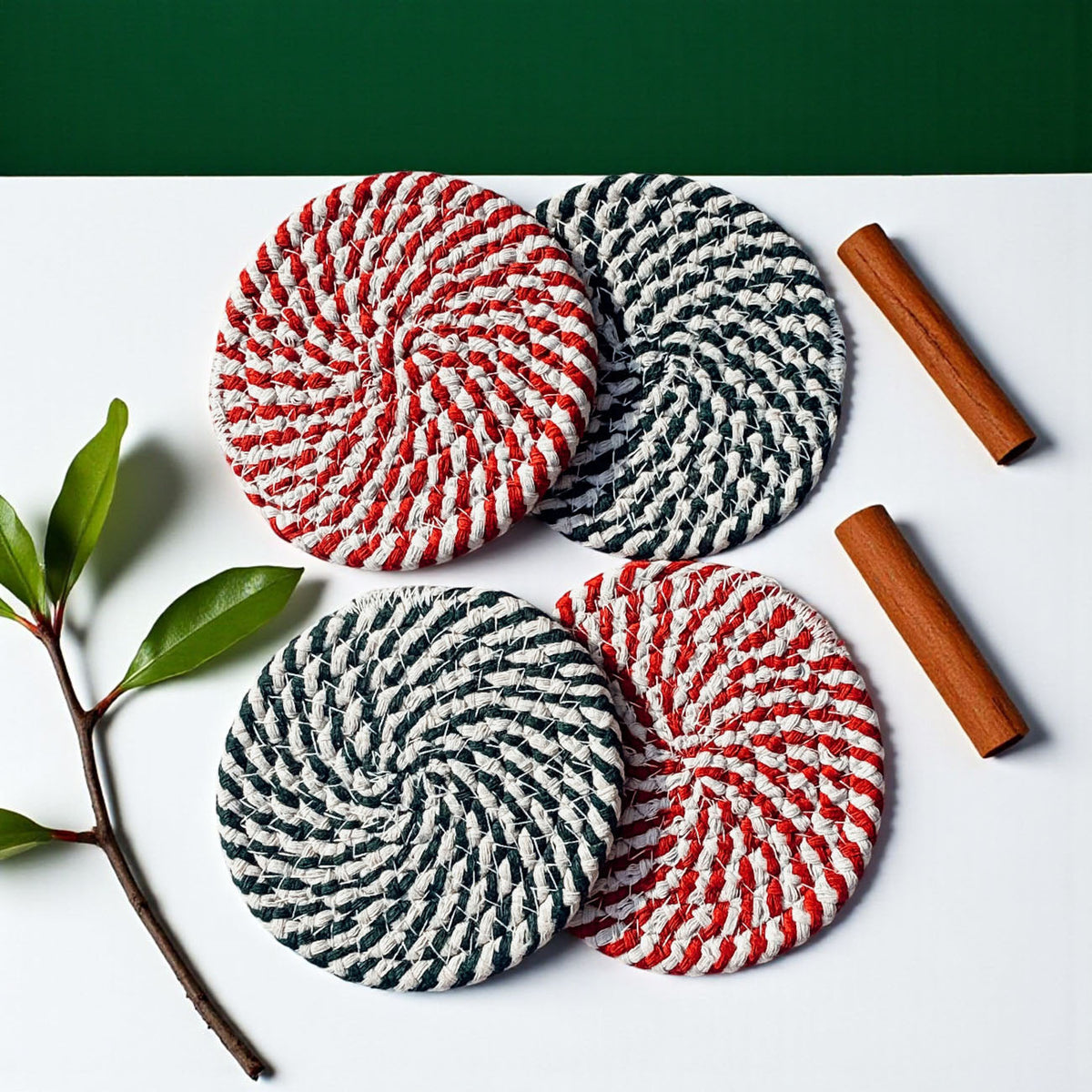 Four braided coasters, red/white and teal/white stripes, laid on white surface