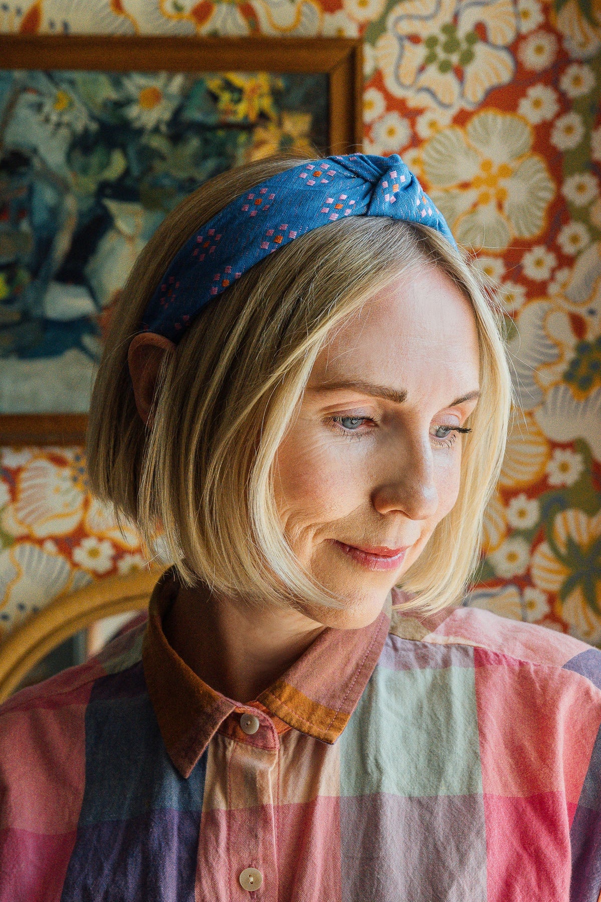 Blue knotted headband worn on hairline, patterned with pink and orange squares