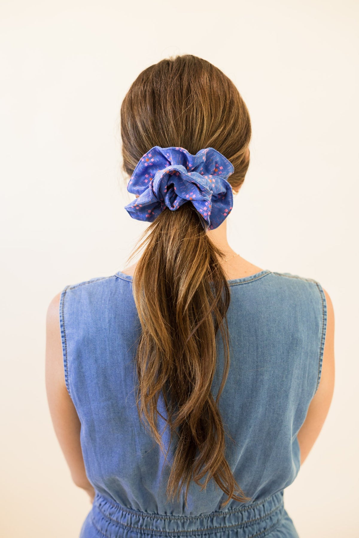 Blue patterned hair scrunchie bow on a ponytail, viewed from behind