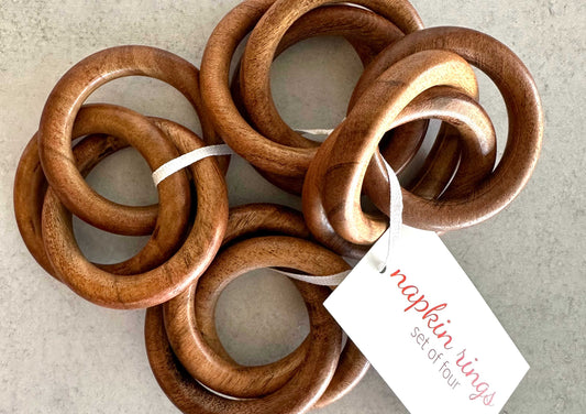 Set of four wood napkin rings, stacked with white product tag on brown bands