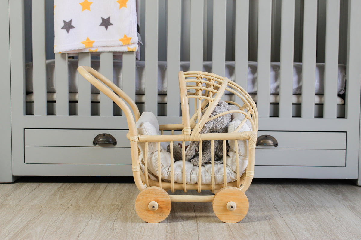 Side view of rattan doll stroller with white bedding and dolls inside