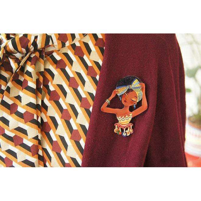African woman brooch pinned on patterned shirt fabric with bead charm dangles