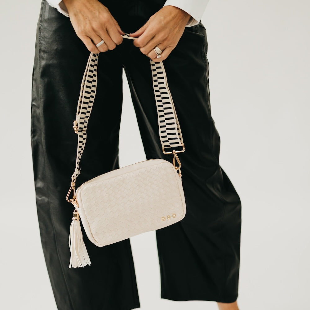 Cream woven camera crossbody bag with gold clasp hardware and white tassel