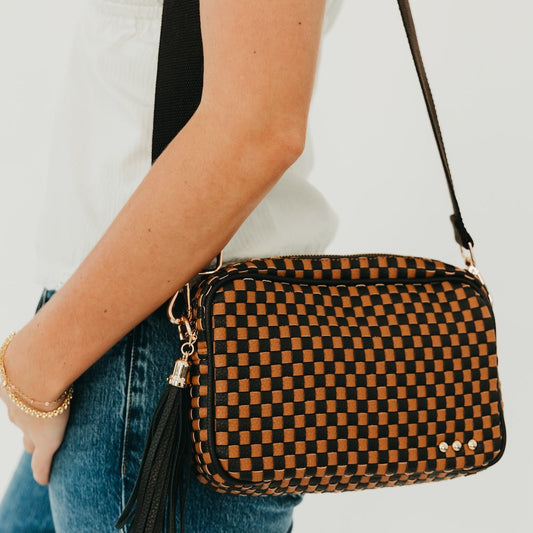 Woven willow camera crossbody bag with black and orange check pattern, tassel detail
