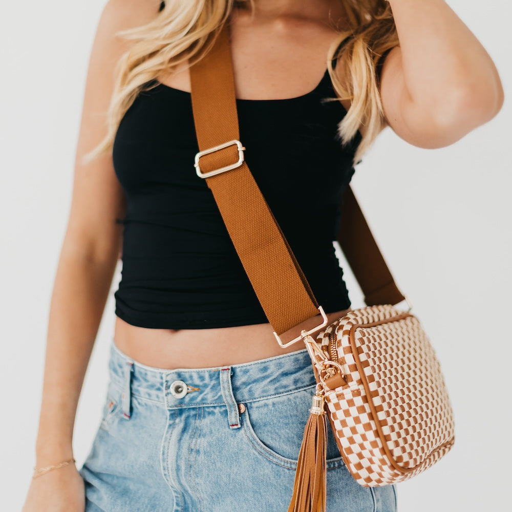 Woven camera crossbody bag with brown-and-cream checkered pattern and tassel