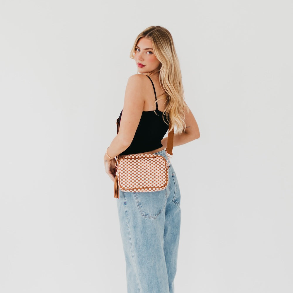 Woven camera crossbody bag in orange-and-white check pattern with zip top.