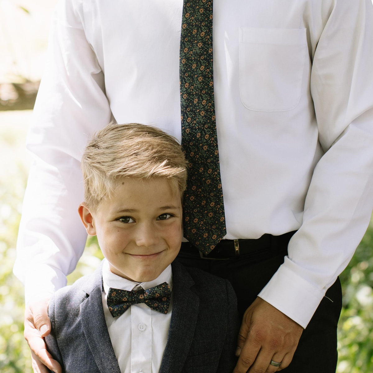 Navy and orange floral bow tie and matching patterned necktie worn with white shirt.
