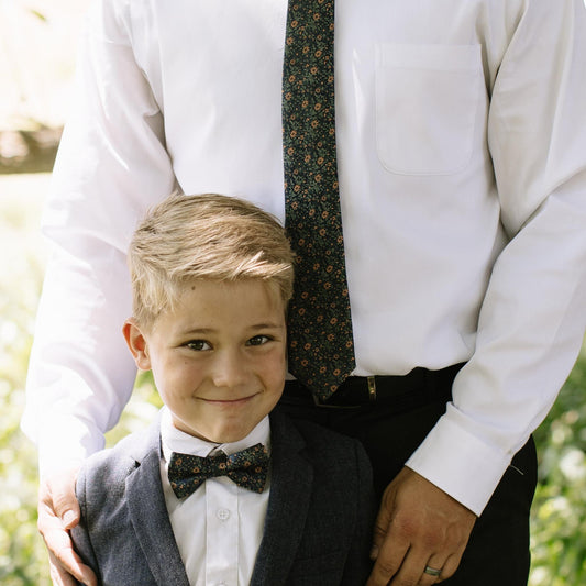 Boys bow tie worn with white shirt and dark vest; navy with orange floral details