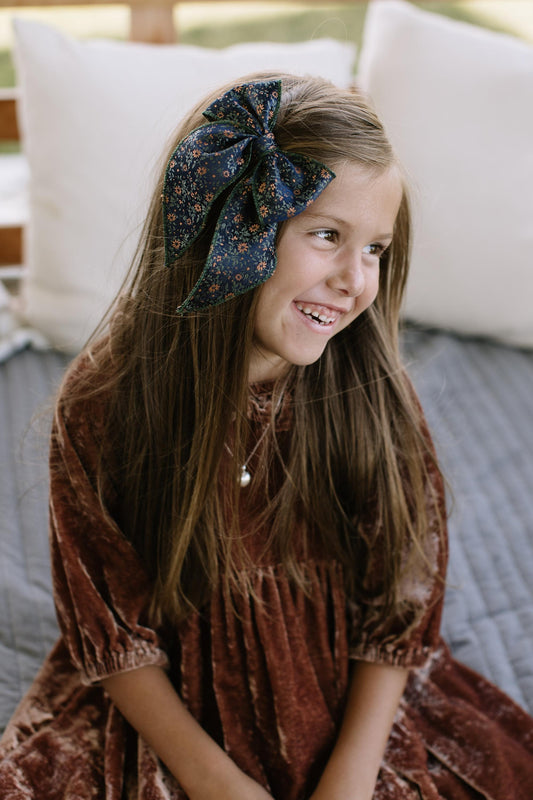 Floral hair bow in dark green worn on a child’s head