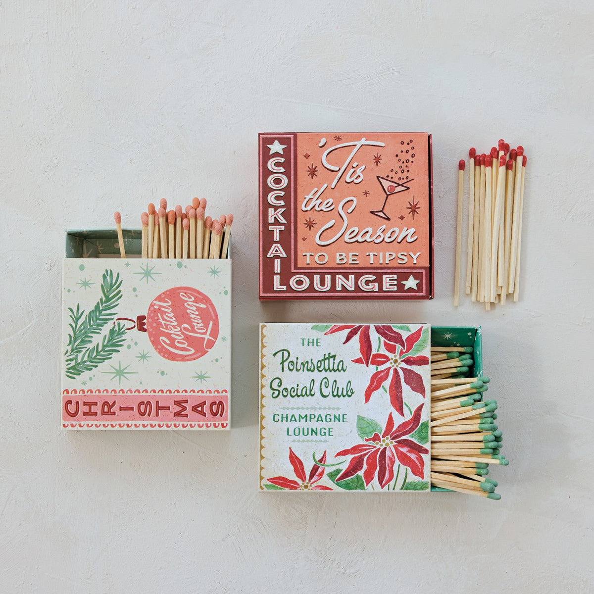 Two holiday matchboxes with exposed matchsticks and festive red-and-green patterns