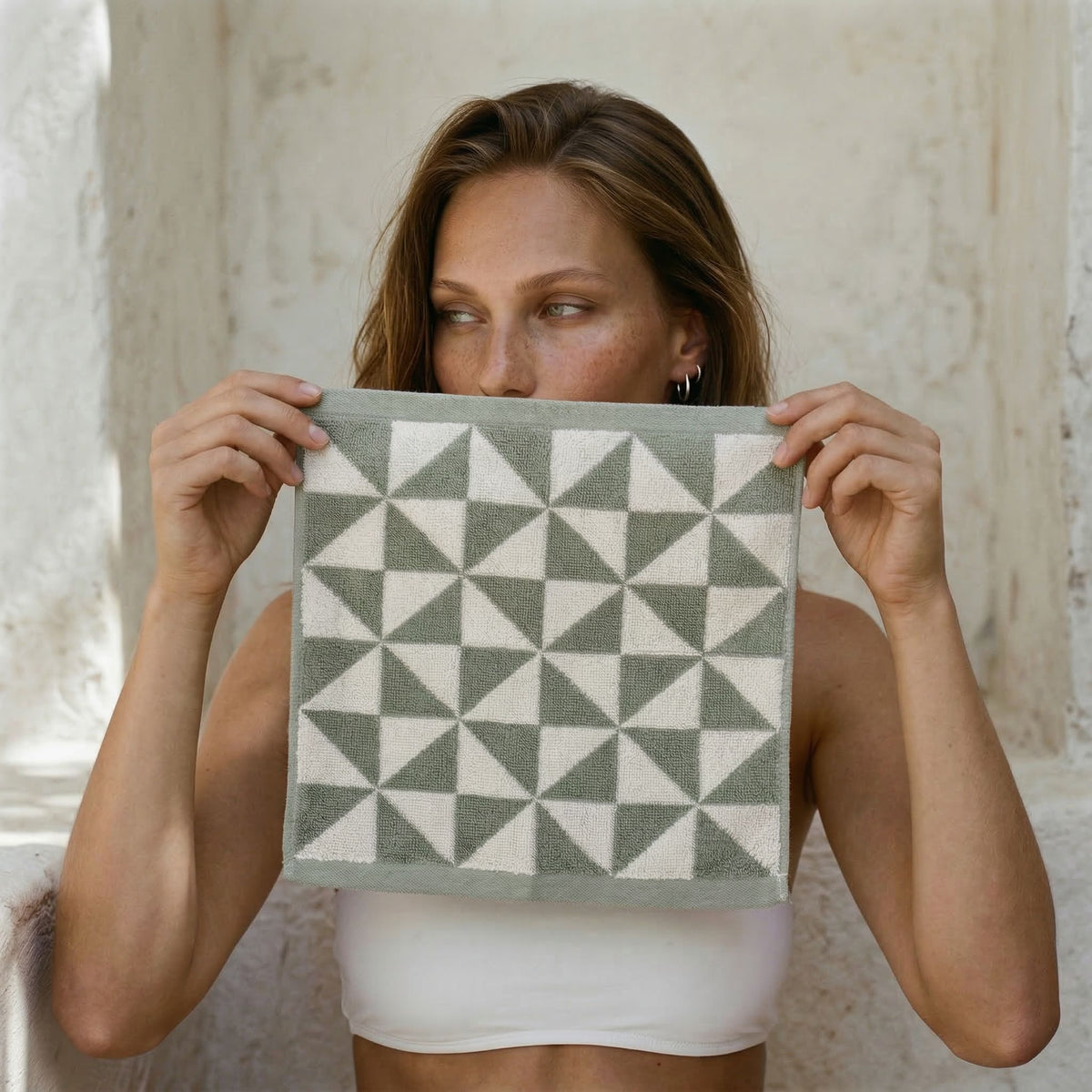 Cotton towel with green geometric pattern on a light background, held up