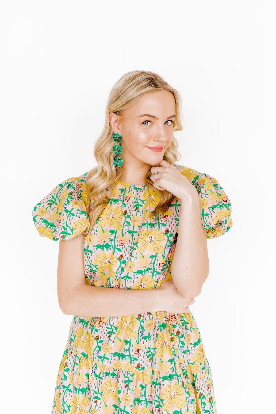 Three-tier green clover dangle earrings with white centers, worn by model
